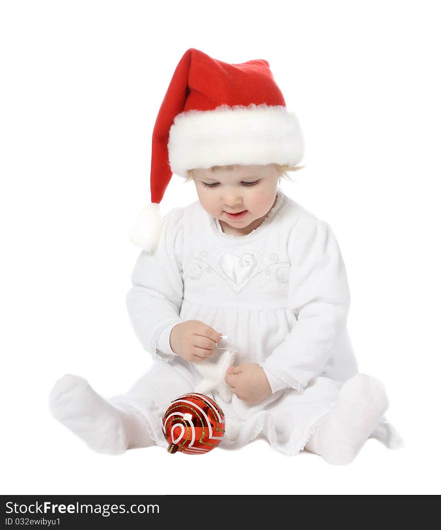 Smart baby girl in Santa's hat playing with New Year toys. Smart baby girl in Santa's hat playing with New Year toys