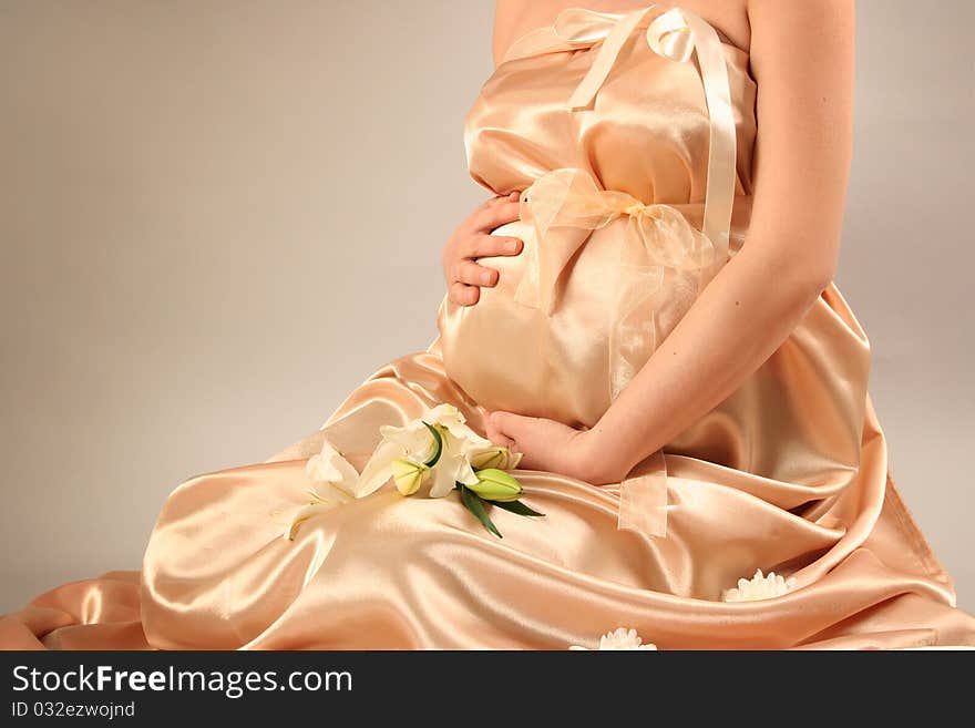 Beautiful pregnant woman wrapped in golden silk. Beautiful pregnant woman wrapped in golden silk