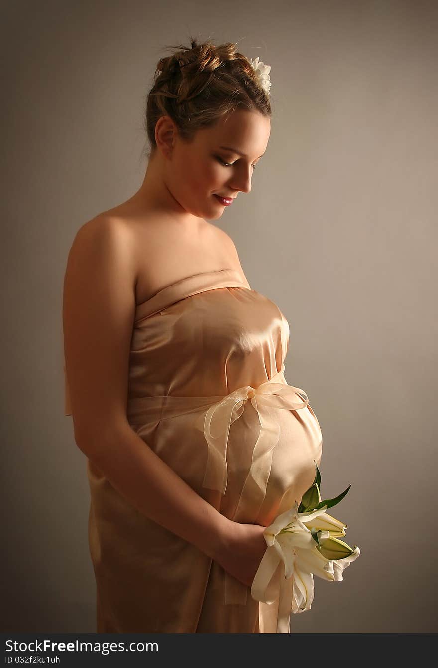 Beautiful pregnant woman wrapped in golden silk. Beautiful pregnant woman wrapped in golden silk