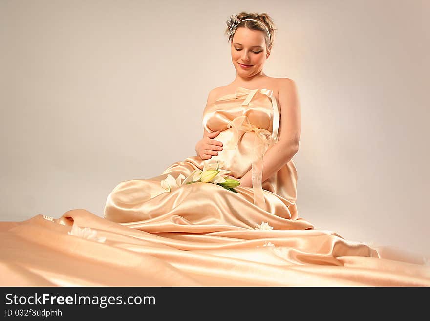 Beautiful pregnant woman wrapped in golden silk. Beautiful pregnant woman wrapped in golden silk