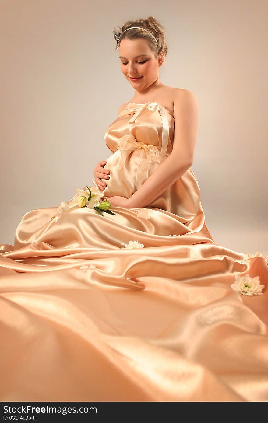 Beautiful pregnant woman wrapped in golden silk. Beautiful pregnant woman wrapped in golden silk