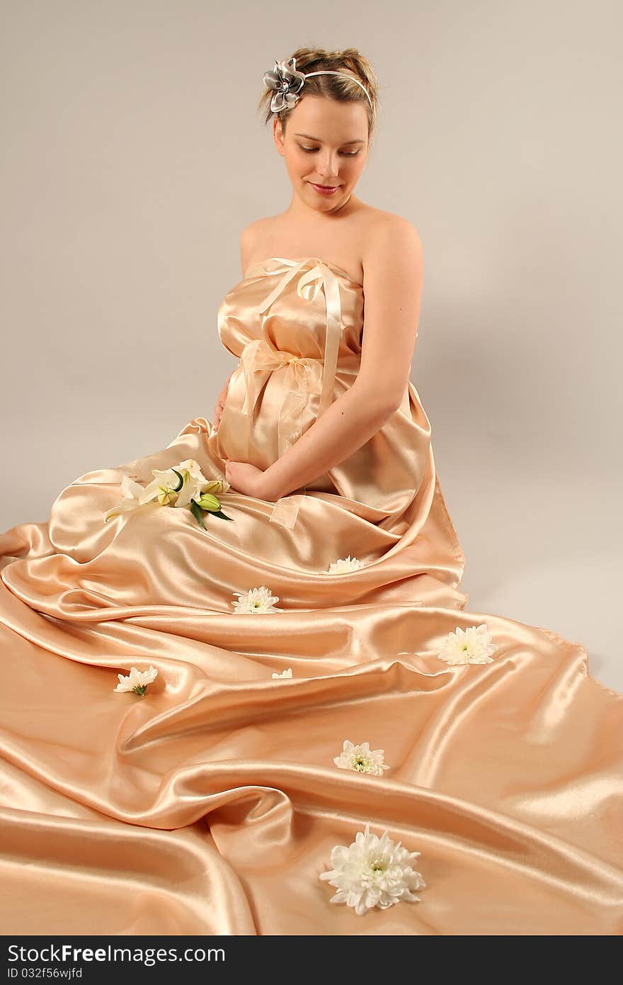 Beautiful pregnant woman wrapped in golden silk. Beautiful pregnant woman wrapped in golden silk