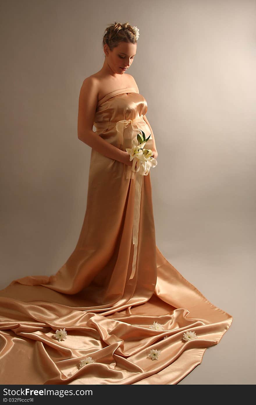 Beautiful pregnant woman wrapped in golden silk. Beautiful pregnant woman wrapped in golden silk