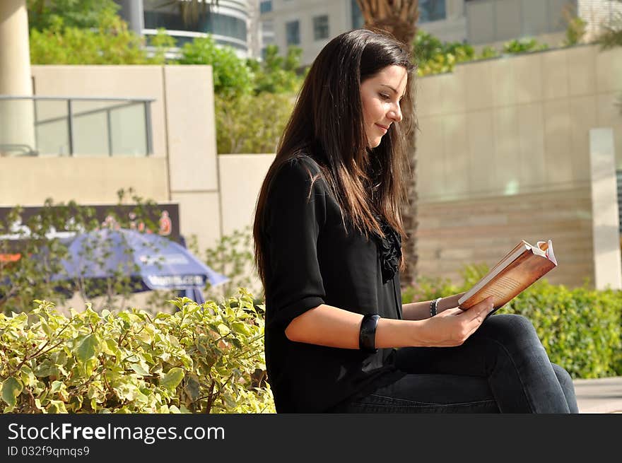 Young beautiful woman reading a book in park