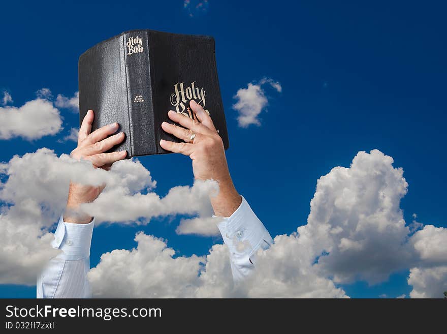 Hands holding up Bible in sky with clouds. Hands holding up Bible in sky with clouds