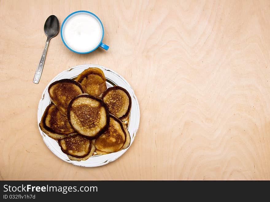 Pancakes on a dish together with sour cream. Pancakes on a dish together with sour cream