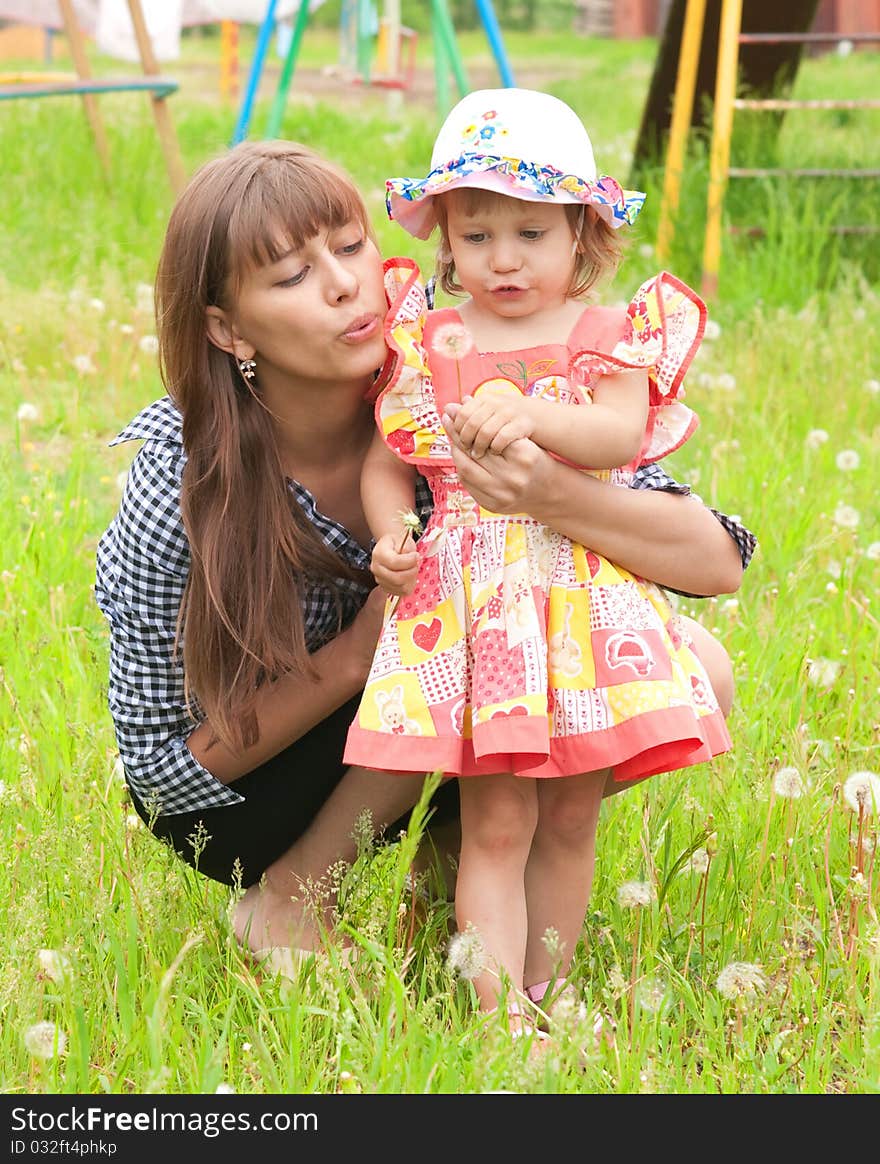 Mum and the daughter blow on a dandelion. Mum and the daughter blow on a dandelion