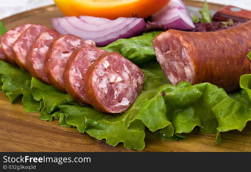 Breakfast close-up. Slices of sausage on the wooden plate with knife