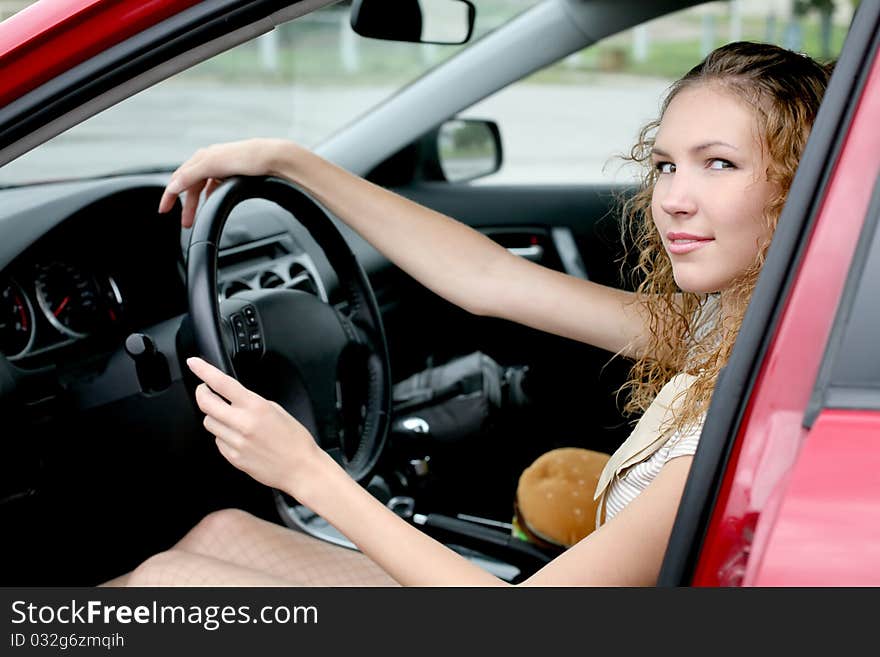 Young beautiful woman driver in red shiny car outdoors smiling. Young beautiful woman driver in red shiny car outdoors smiling