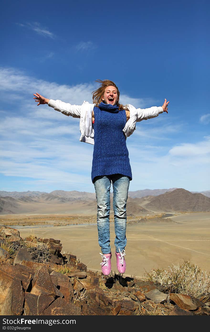 The jumping smiling girl against a mountain landscape in mongolia