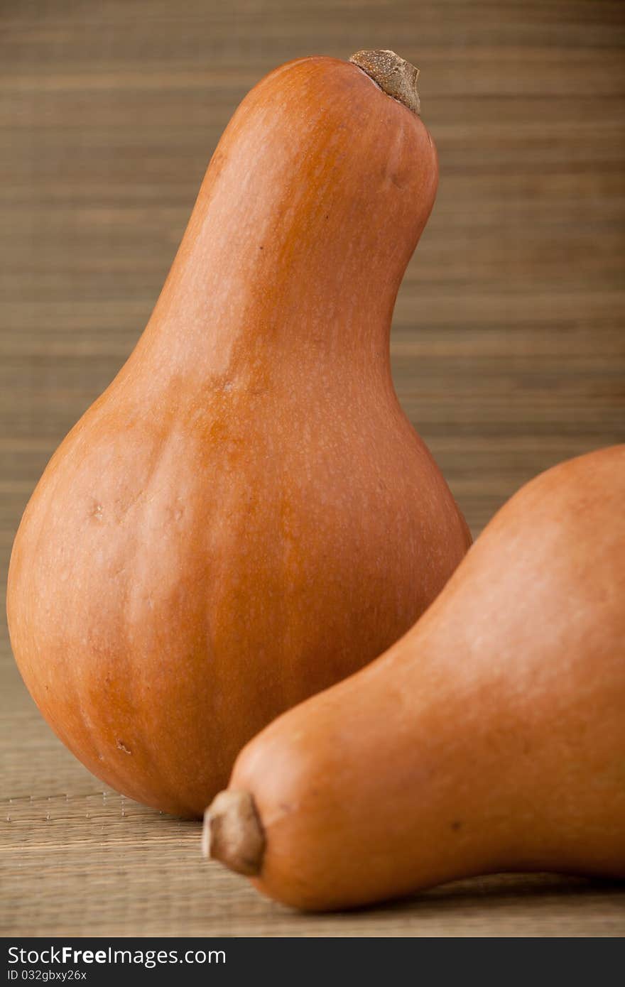 Group of ripe orange gourds on rural straw woven surface and stripy background. Group of ripe orange gourds on rural straw woven surface and stripy background