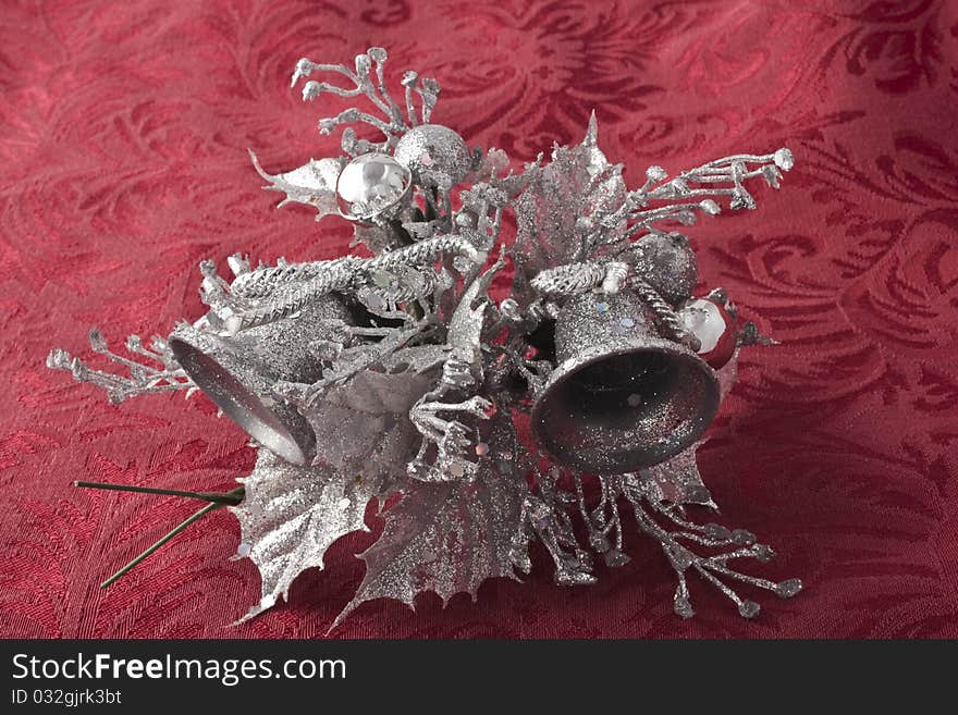 Silverbells on red brocade background with silver leaves and berries