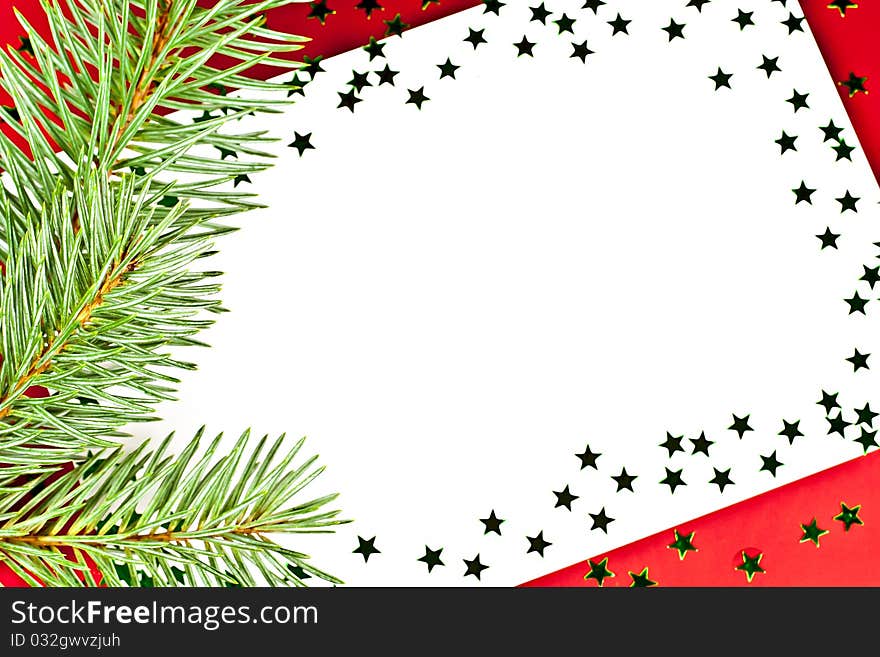 On a red background white greeting card with spruce twigs and green stars. On a red background white greeting card with spruce twigs and green stars.