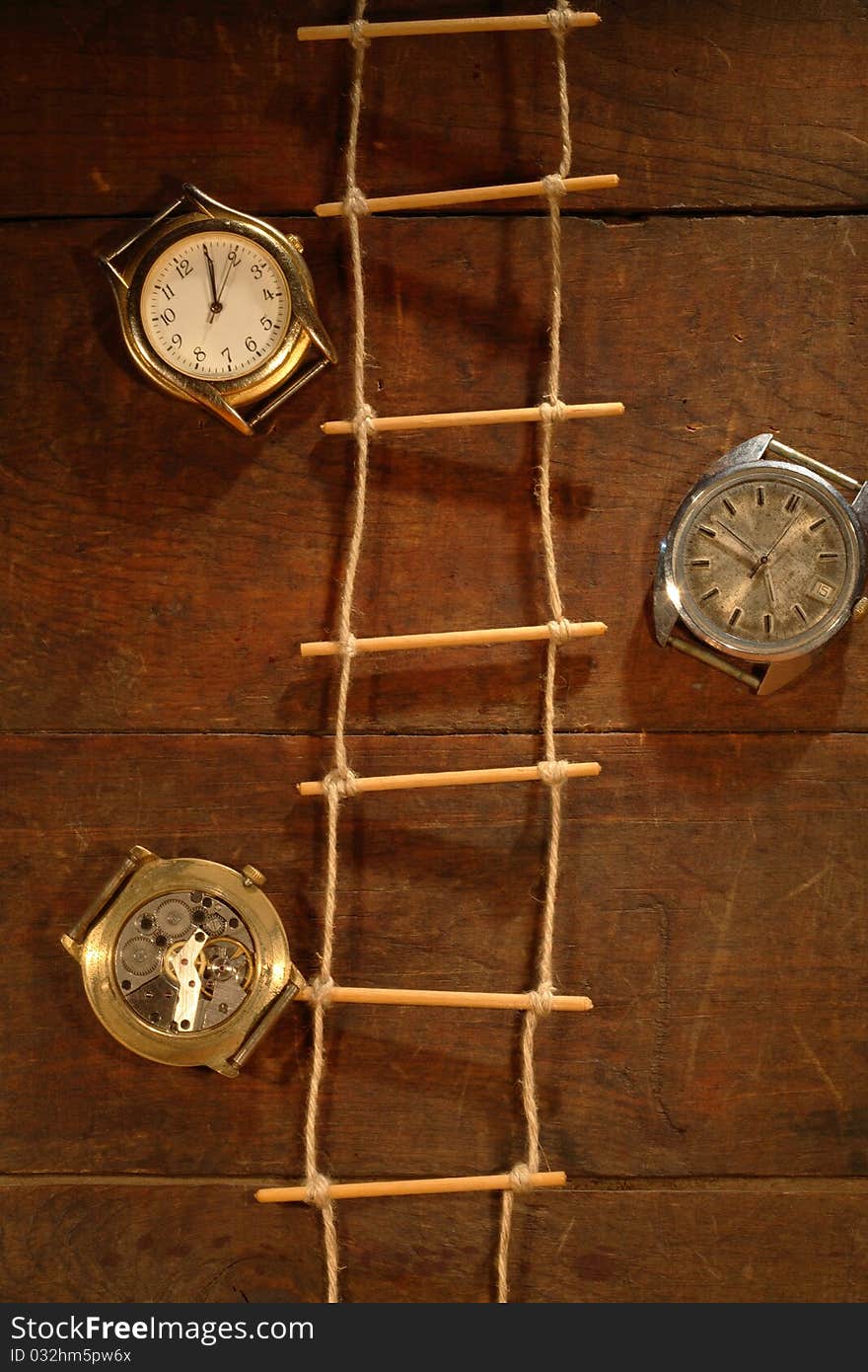 Rope ladder hanging on wooden background with old watches. Rope ladder hanging on wooden background with old watches