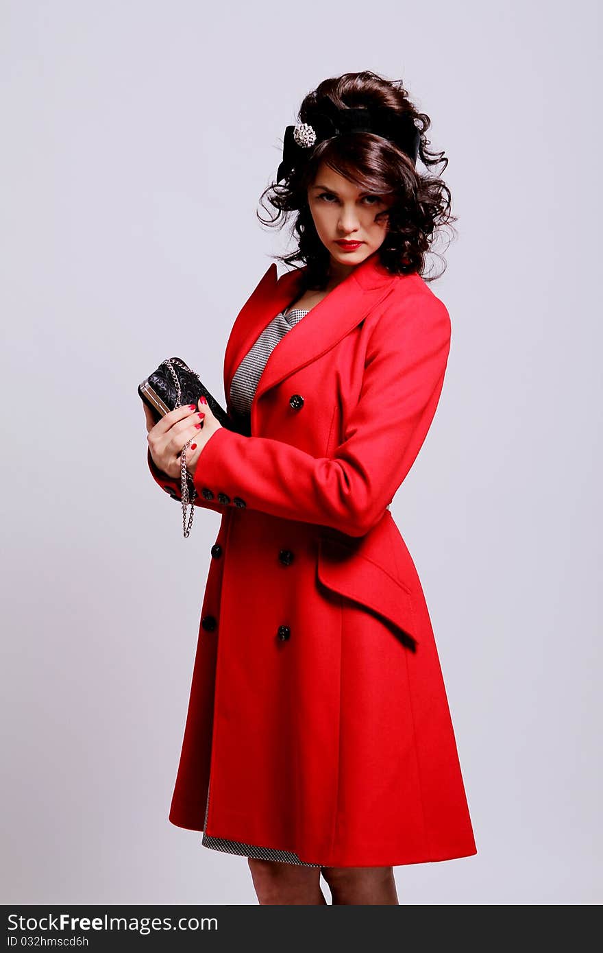 Beautiful young woman in retro coat posing on white background