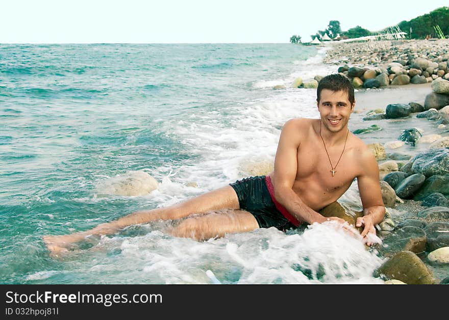 Yang male model lying down on beach. Yang male model lying down on beach