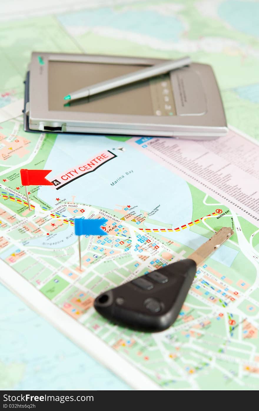 Road map with a red and blue flag, car keys, electronic organizer. closeup. Road map with a red and blue flag, car keys, electronic organizer. closeup.