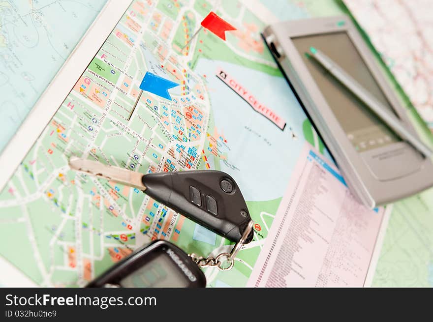 Road map with a red and blue flag, car keys, electronic organizer. closeup. Road map with a red and blue flag, car keys, electronic organizer. closeup.