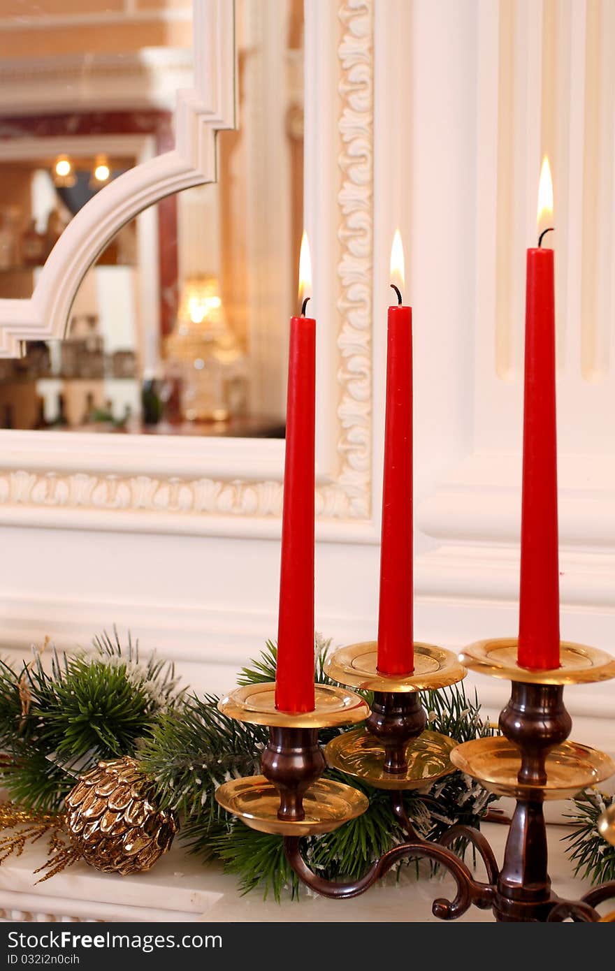 Candles in a candlestick on a fireplace against a mirror.