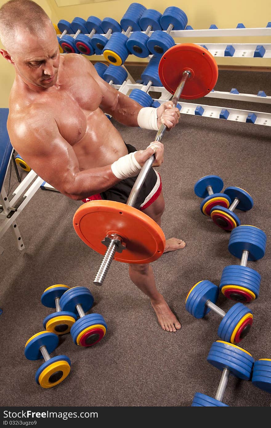 Fitness - powerful muscular man with a bar weights in hands training