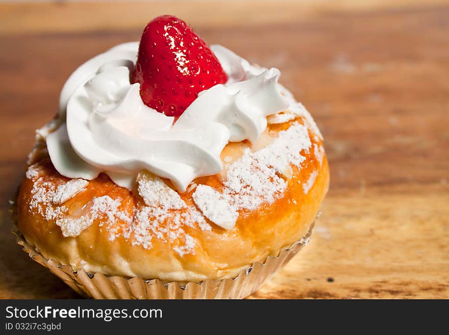 Strawberry cupcake with strawberry on top with cream and icing on the table