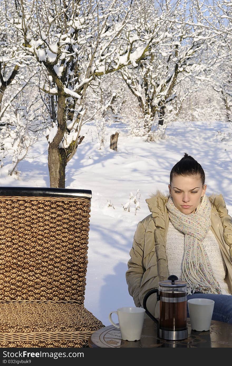 Young female preparing to drink tea, trees with snow on branches in background. Young female preparing to drink tea, trees with snow on branches in background