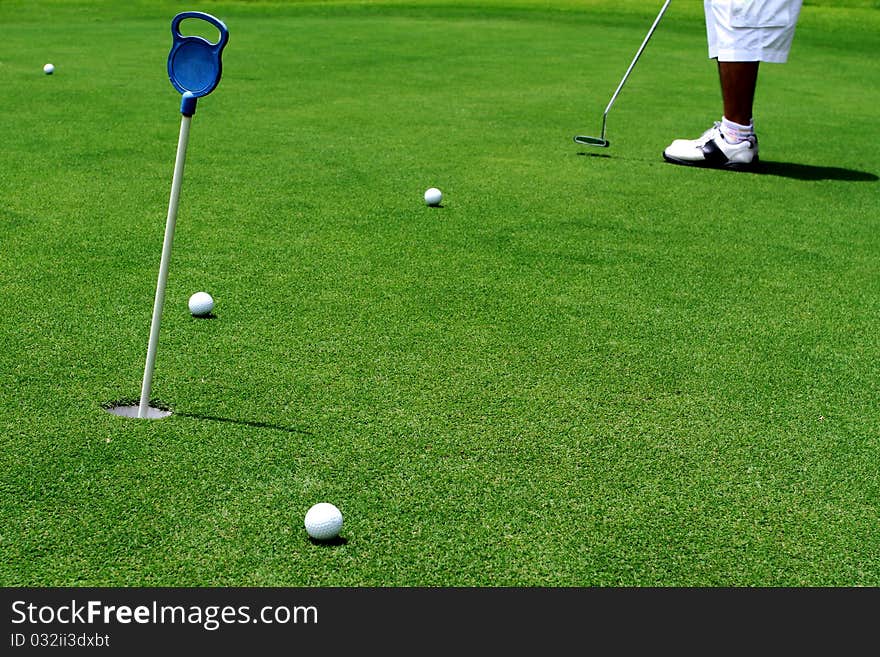 Golfer putting a golf ball in golf course