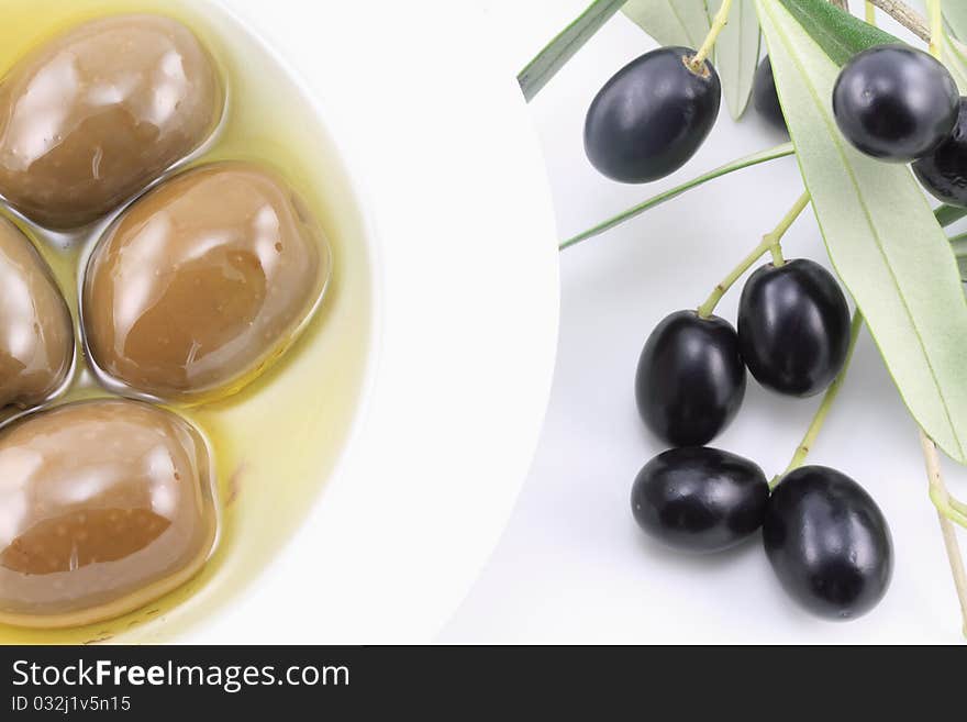 Olives in a bowl with olive oil and olive tree branch