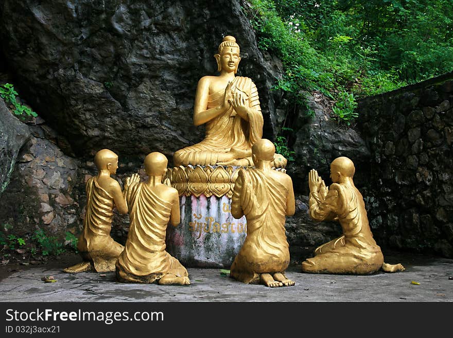 Gold sitting buddha surrounded by monk students