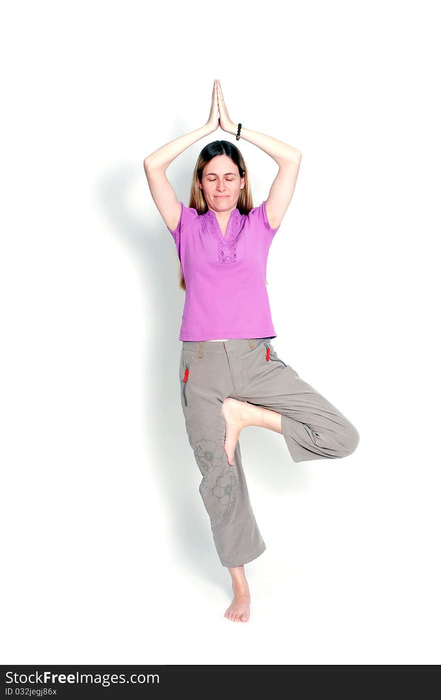 Young woman practicing yoga in the tree posture with closed eyes