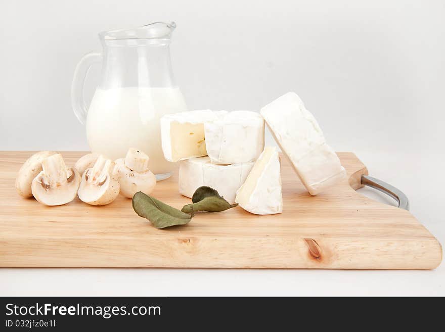 Still-life with white cheese, milk and field mushrooms on the wooden desk