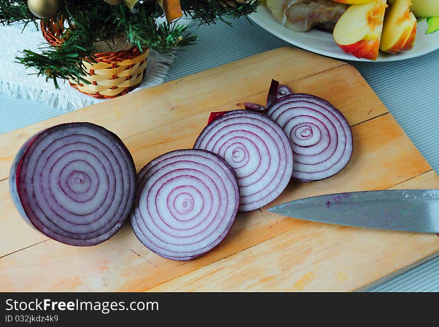 Some pieces of onion with knife on the wooden board