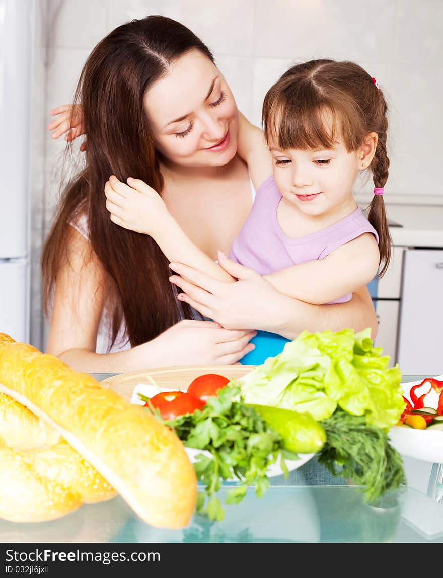 Young mother and her five year old daughter cook together on the kitchen at home. Young mother and her five year old daughter cook together on the kitchen at home