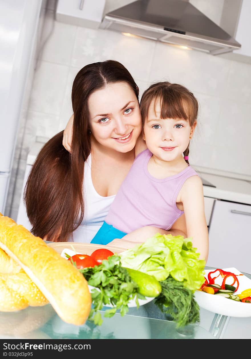 Young mother and her five year old daughter cook together on the kitchen at home. Young mother and her five year old daughter cook together on the kitchen at home