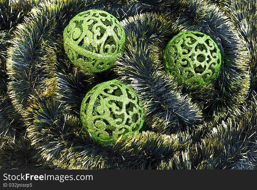 Green carved christmas balls on tinsel background