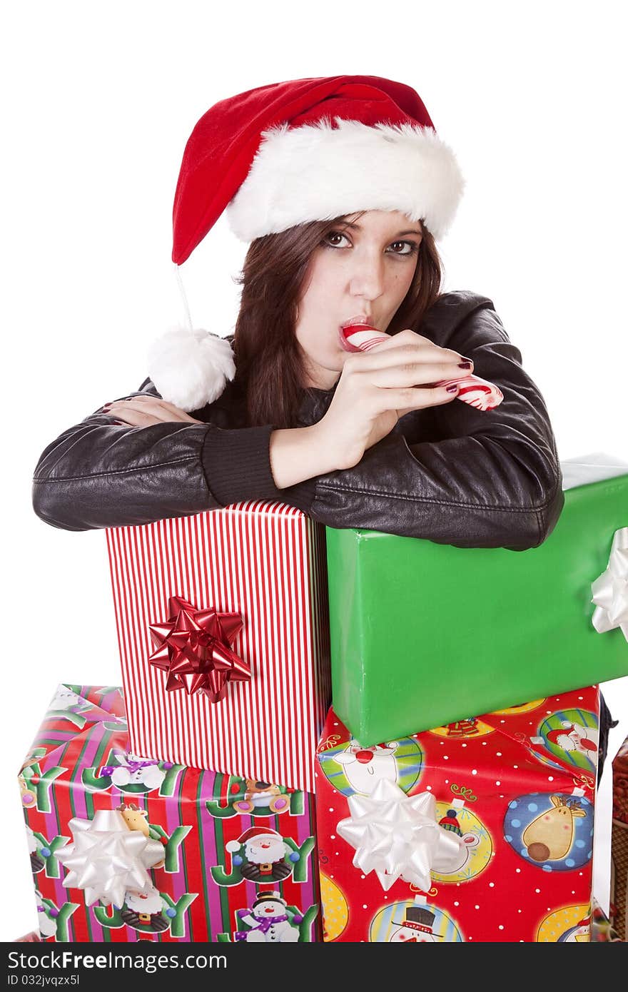 A woman is licking a candy stick by a stack of presents. A woman is licking a candy stick by a stack of presents.