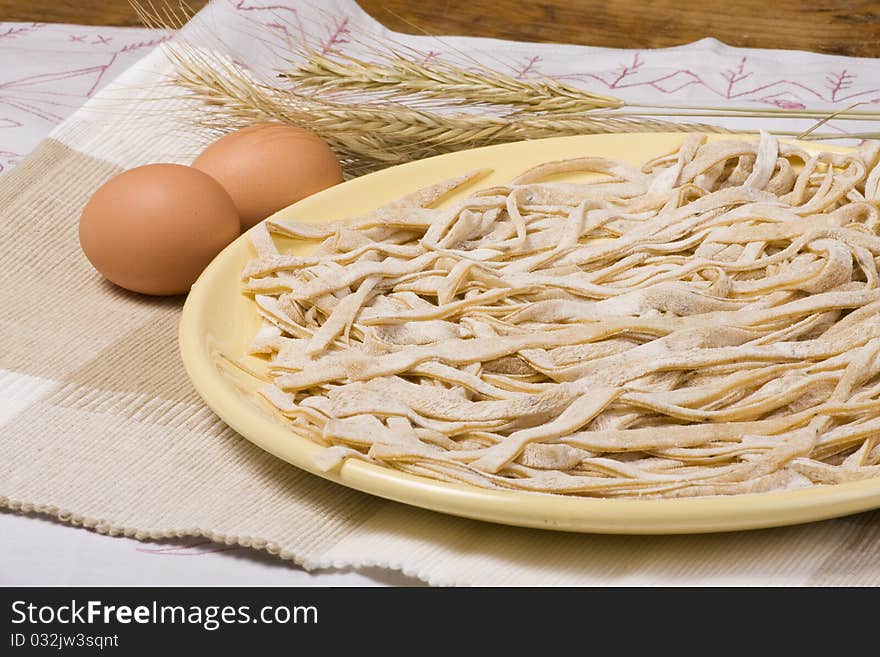 Uncooked homemade egg pasta with mushrooms. Cut into tagliatelle stripes. Uncooked homemade egg pasta with mushrooms. Cut into tagliatelle stripes.