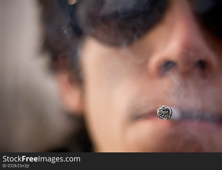 Caucasian man holding 1 cigar in his mouth.