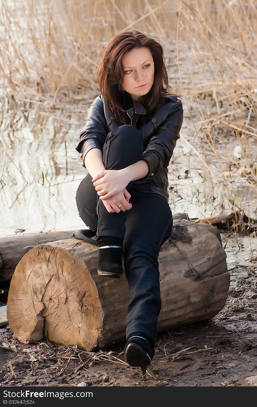 A beautiful girl is sitting on a stump