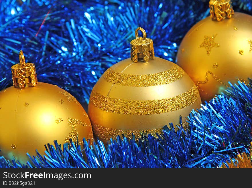 Golden Christmas baubles in blue tinsel. Golden Christmas baubles in blue tinsel