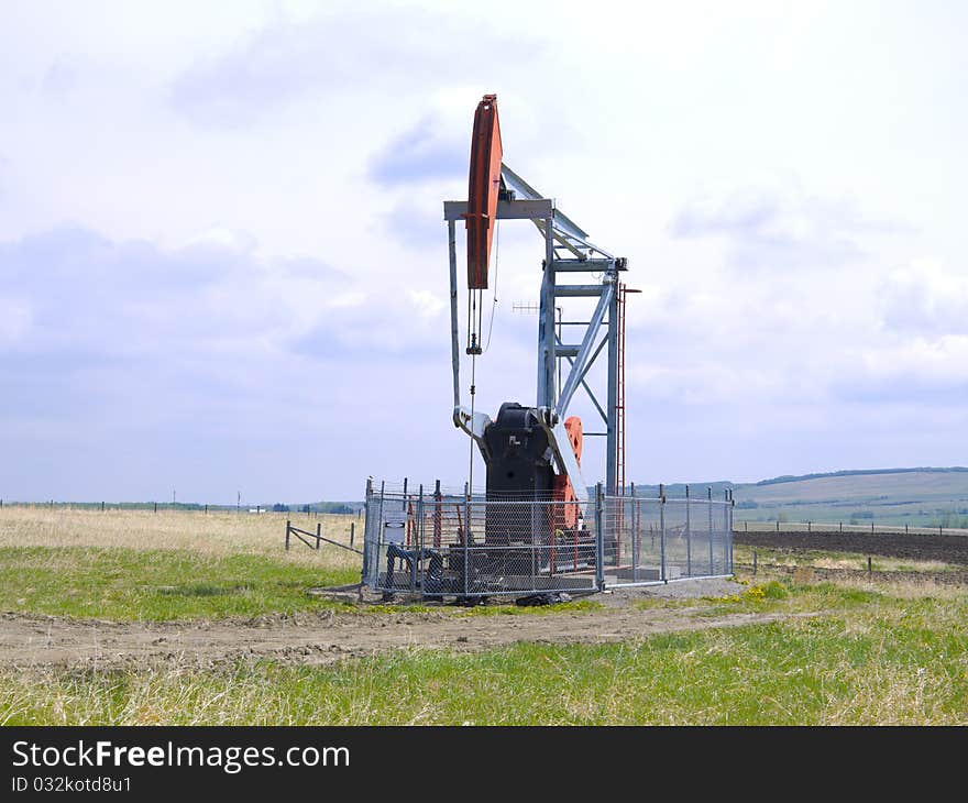 Oil pump in a fenced area located in a barren farmers field. Oil pump in a fenced area located in a barren farmers field.