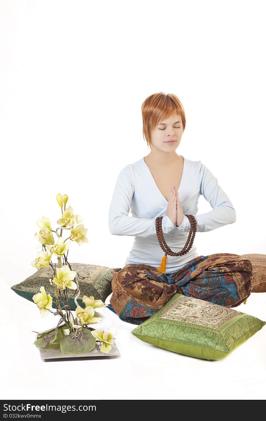 Girl meditating on a white background mong pillows and flowers orchids