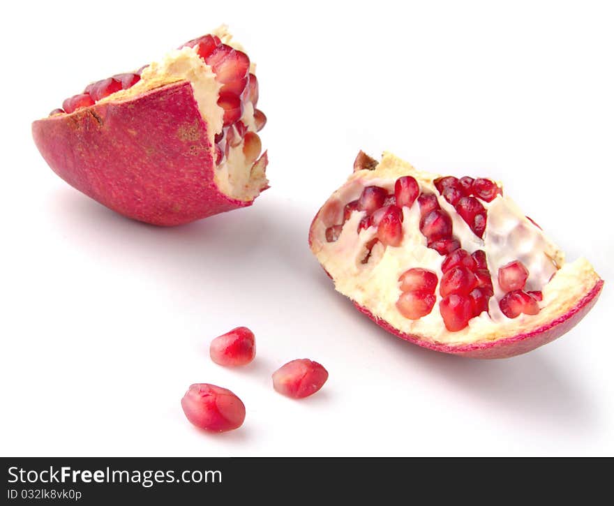 Parts of pomegranate with grains in foreground against white. Parts of pomegranate with grains in foreground against white