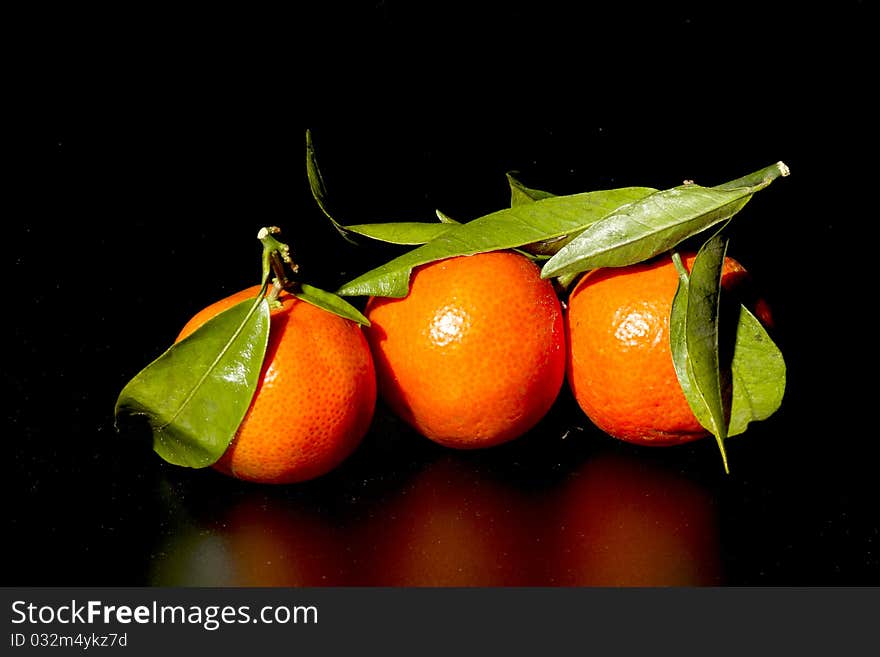 Clementine with leaves on a black background. Clementine with leaves on a black background