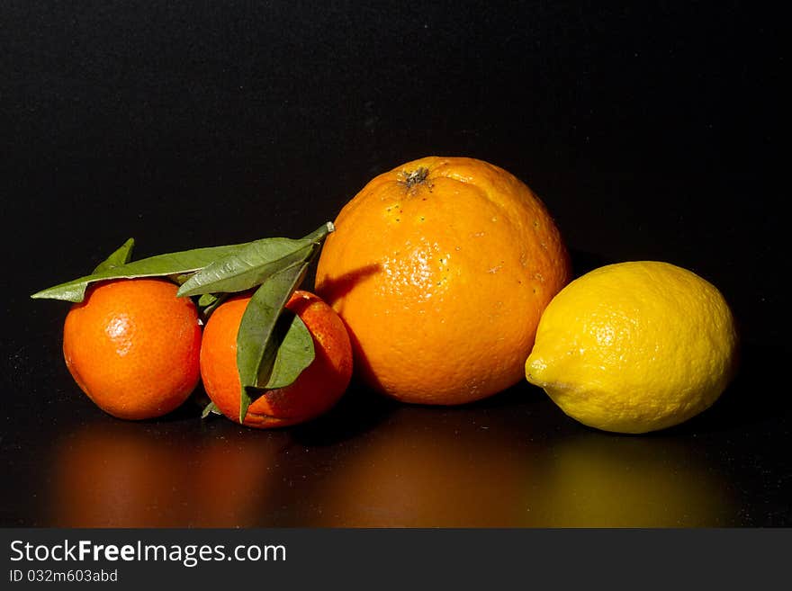 Clementine orange and lemon on black background. Clementine orange and lemon on black background