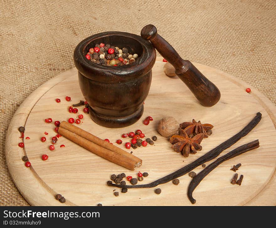 Mix of the spices on the wooden desk with old mortar. Mix of the spices on the wooden desk with old mortar