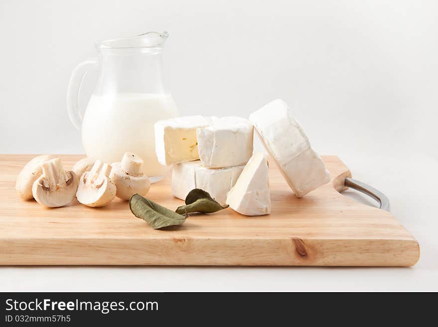 Still-life with white cheese, milk and field mushrooms on the wooden desk