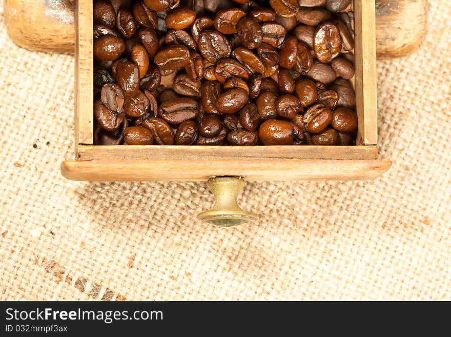 Fragrant fried coffee beans in the old wooden coffee grinder. Fragrant fried coffee beans in the old wooden coffee grinder