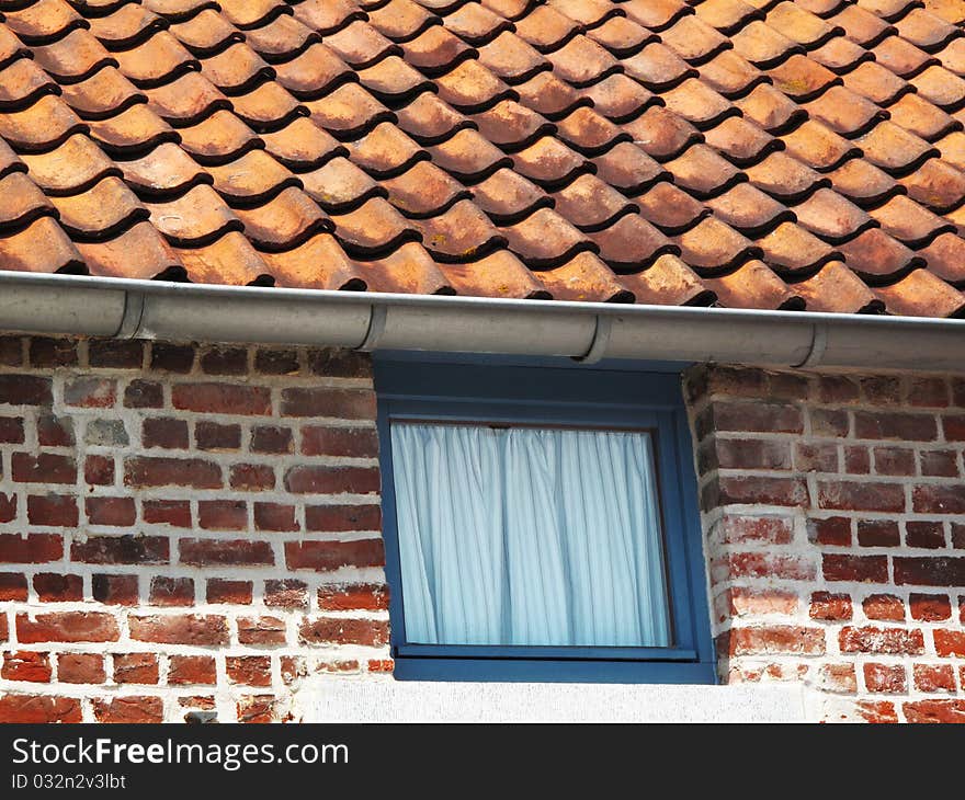 Roof and wall of a brick building with a window