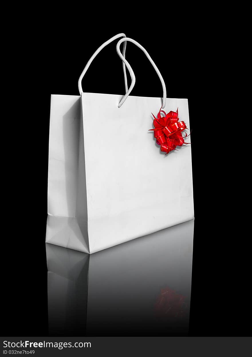 White paper bag and red bow on reflect floor and black background